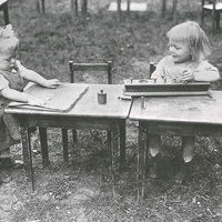 Two year olds in the garden of the Children's House Berlin-Lankwitz, 1919-22. The little girl on the left is practising buttoning on one of the dressing frames; the child on the right is busy with the cylinder insets of different diameters. This photograph from 1920 was also published in 1927 in the Berliner Illustrirte Zeitung -  T. Müller, R. Schneider, <em>Lehrmaterialien 1913-1935. Möbel und Architektur. Techning Meterials 1913-1935. Furniture and Architecture</em>, München, Prestel Verlag, 2002, p.90$$$447