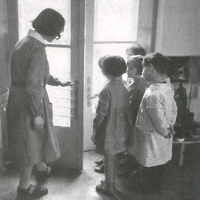 An exercise in opening doors. Children's House on Rudolfsplatz, Vienna. Photograph taken around 1934. The teacher is demonstrating how to do it using her door handle at normal height. The children have their own handle lower down the right-hand door to enable them to practise - T. Müller, R. Schneider, <em>Lehrmaterialien 1913-1935. Möbel und Architektur. Techning Meterials 1913-1935. Furniture and Architecture</em>, München, Prestel Verlag, 2002, p.81$$$425