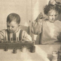 Children abosorbed in sensory exercises with cylinderinsets ans sound boxes in a Berlin Children's House. Postcard published by the DMG (German Montessori Society), around 1927 - T. Müller, R. Schneider, <em>Lehrmaterialien 1913-1935. Möbel und Architektur. Techning Meterials 1913-1935. Furniture and Architecture</em>, München, Prestel Verlag, 2002, p.21.$$$367